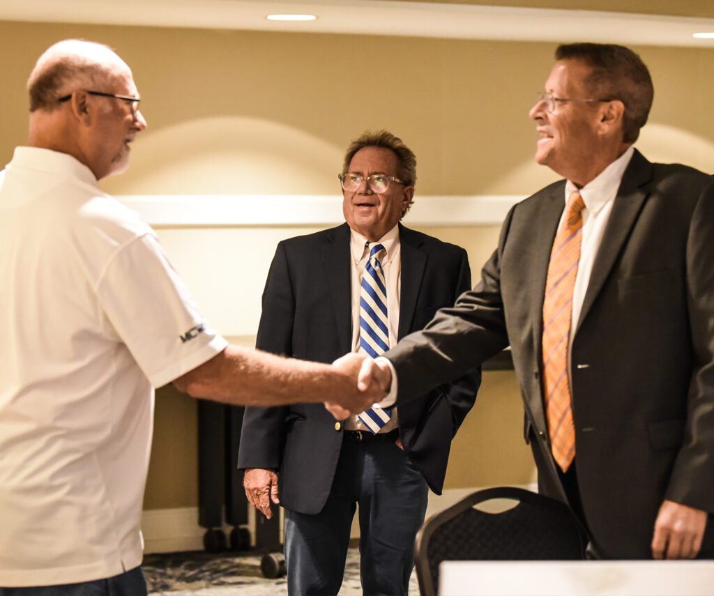Two men shake hands at the MCWCF Conference.