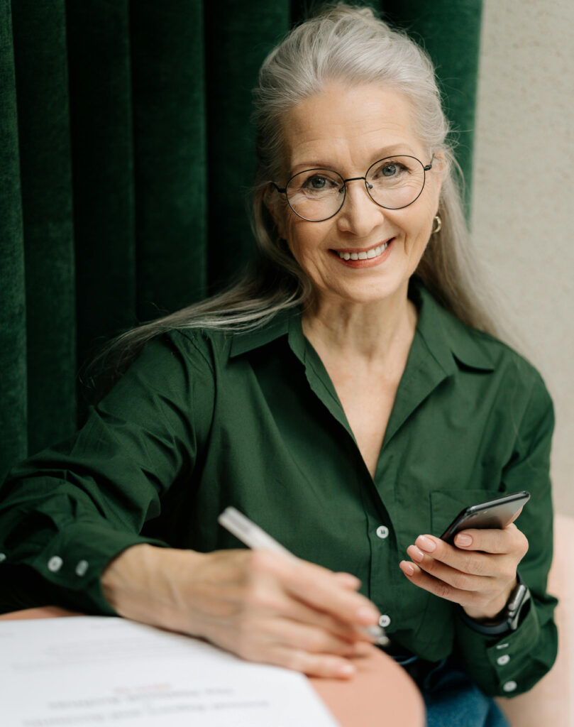 Image of a woman filling out paperwork at a table while holding phone