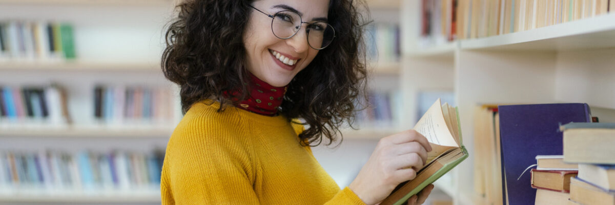 Woman in yellow sweater browses books at the library.